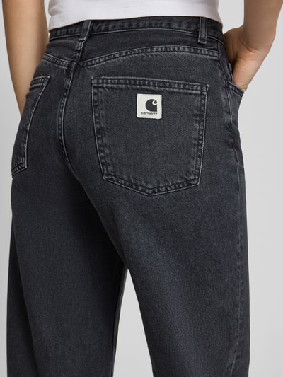 Kobiece model prezentuje Wide Leg Jeans im 5-Pocket-Design Modell 'Jane' od Carhartt Work In Progress, czarne, bawełna, szerokość w rozmiarze 27: 37 cm, długość wewnętrzna nogawki 78 cm, detal z logo na tylnej kieszeni, zapięcie na guzik i zamek błyskawiczny, krój wide fit, ujęcie z tyłu, zbliżenie na biodro