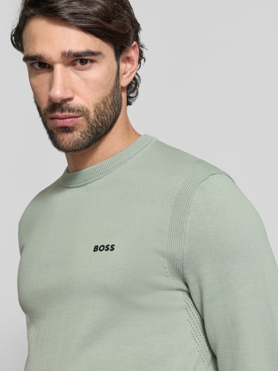 Männermodel trägt Regular Fit Strickpullover aus reiner Baumwolle Modell 'EVER-X' von BOSS Green in Hellgrün, Nahaufnahme Oberkörper.