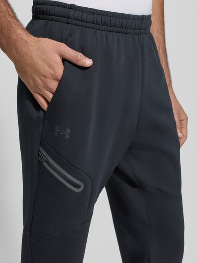 Männermodel trägt Sweatpants mit Logo Modell 'Unstoppable' van Under Armour, katoenmix, regular fit, elastische tailleband, detailopname heup.