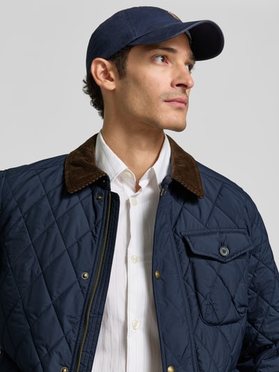 Männermodel trägt Regular Fit Steppjacke mit Druckknopfleiste von Polo Ralph Lauren, unifarben, Umlegekragen, Nahaufnahme Oberkörper.