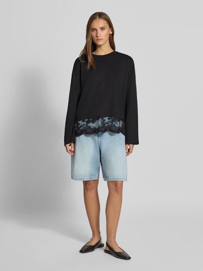 Vrouwenmodel draagt zwart Regular Fit Langarmshirt uit puur katoen model 'VIVVI' van ONLY, dames shirt met lange mouwen, volledig lichaamsaanzicht van voren.