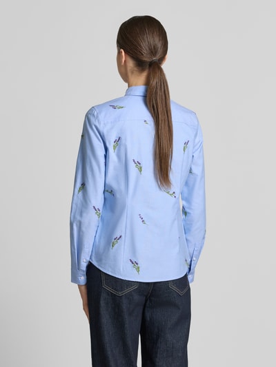 Modelka kobieca ma na sobie Hemdbluse mit Motiv-Stitchings od Christian Berg Woman, błękitna bawełna z kolorowymi haftami, prosty krój, tył całej sylwetki.