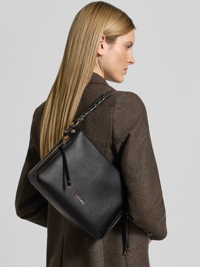 Frauenmodel trägt Handtasche in Leder-Optik Modell 'Gihen' von Liu Jo White mit Logo-Detail, abnehmbare Schulterriemen, Ganzkörperansicht Rückansicht
