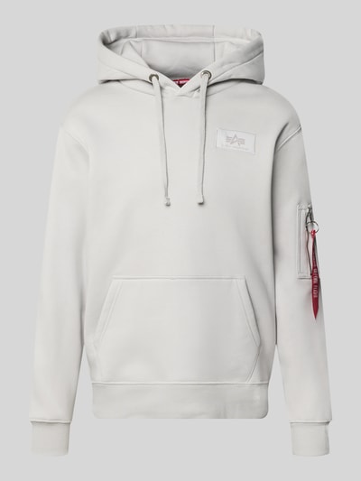 Produktfoto, Hoodie mit Känguru-Tasche von Alpha Industries z mieszanki bawełny, luźny krój, kaptur z tunelem, naszywka z logo, kieszeń na rękawie z aplikacją z metką, kieszeń kangurka, długość tyłu w rozmiarze M: 67 cm, długość rękawów w rozmiarze M: 64 cm, jasnoszary kolor, proste kształty, gładka tekstura