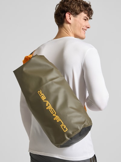 Männermodel trägt olivgrüne Tasche mit Riemen und Label-Print von Quiksilver, Herren Tasche, Ganzkörperansicht von hinten.