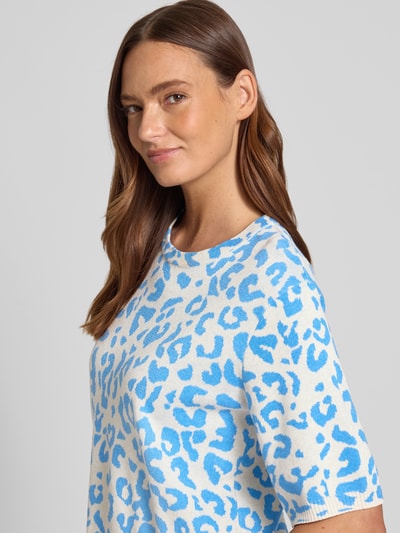 Frauenmodel trägt Relaxed Fit Shirt aus Viskose-Anteil Modell 'Mayas' von Vila, blau-weißer Allover-Animal-Print, Strick-Optik, Halbarm, Nahaufnahme Oberkörper.