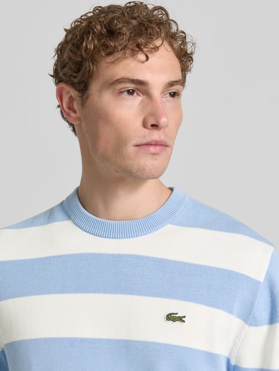 Männermodel trägt Regular Fit Pullover aus reiner Baumwolle von Lacoste, Optik:Allover-Muster, Label-Patch, Nahaufnahme Oberkörper.