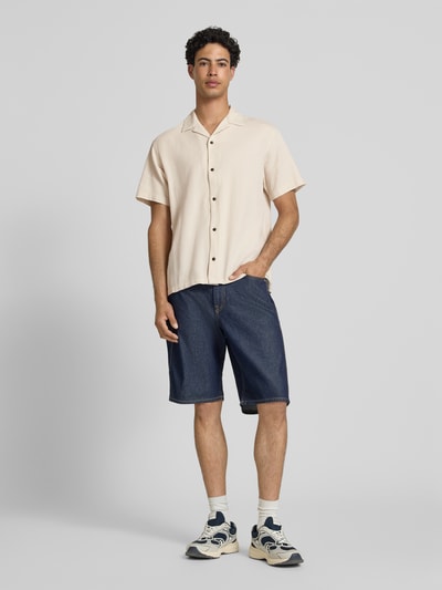 Männermodel trägt Regular Fit Freizeithemd mit Strukturmuster Modell 'Global' von Jack & Jones aus reiner Baumwolle, kurzärmelig, Reverskragen, durchgehende Knopfleiste, beige Farbe, Ganzkörperansicht von vorne.
