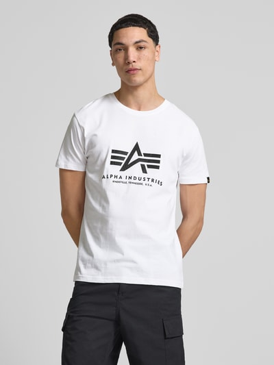 Männermodel trägt Herren T-Shirt mit Label-Detail Modell 'Basic' von Alpha Industries, Weiß, Reine Baumwolle, Gerader-Schnitt, Rundhalsausschnitt, Rückenlänge bei Größe M 67 cm, Ganzkörperansicht von vorne.