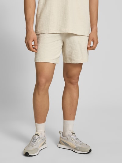 Männermodel trägt Shorts mit Logo-Stitching von PUMA PERFORMANCE in Beige mit Strukturmuster, gerader Schnitt, Nahaufnahme Oberschenkel.