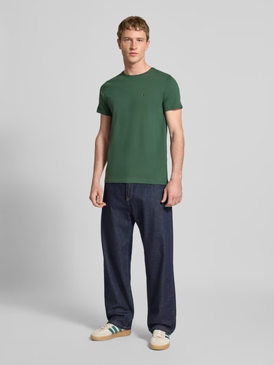 Männermodel trägt Regular Fit T-Shirt aus reiner Baumwolle von Tommy Jeans, Optik: unifarben, Logo-Stitching, Ganzkörperansicht von vorne.