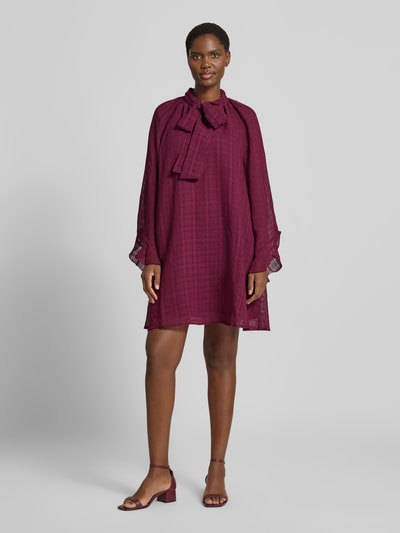 Vrouwenmodel draagt mini-jurk met strik, Loose fit in donkerrood met semitransparante mouwen, onderjurk, Model 'LIANA' van YAS, ruglengte 88 cm, borstwijdte 47 cm, mouwlengte 46 cm, geheel vooraanzicht