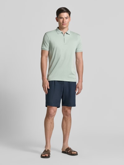 Męski model nosi Regular Fit Poloshirt aus Bio-Baumwoll-Mix Modell 'FAVE' von SELECTED HOMME, efekt: jednolity kolor, krój regular fit, naszywka z logo, kołnierzyk polo, krótki zamek błyskawiczny, krótki rękaw, wykończenie: dżersej interlock, materiał: mieszanka bawełny ekologicznej, Ganzkörperansicht von vorne.