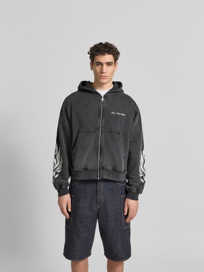 Männermodel trägt Oversized Sweatjacke aus Baumwolle von Don’t Waste Culture in Dunkelgrau mit Känguru-Tasche, Reißverschluss, elastische Abschlüsse, reine Baumwolle, oversized, Ganzkörperansicht von vorne.
