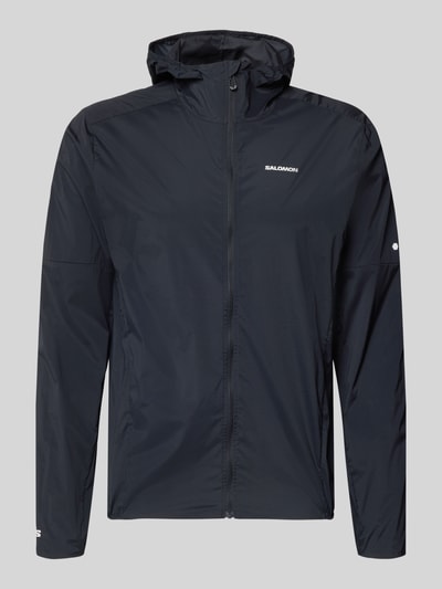 Produktfoto, Windbreaker mit Kapuze und Logo von Salomon, schwarzer Material-Mix mit Stretch-Anteil, Reißverschluss, Regular-Fit, glatte Textur, Herrenmodell, Rückenlänge 72 cm, Schulterbreite 46 cm, Brustweite 56 cm, Ärmellänge 69 cm