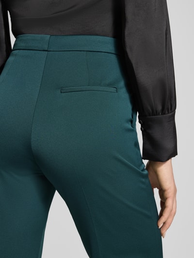 Männermodel trägt Regular Fit Bundfaltenhose mit Viskose-Anteil Modell 'HALENIA' von HUGO, efekt: jednolity kolor, kanty, zapięcie na haftkę i zamek błyskawiczny, krój regular fit, detal z tylną kieszenią. Zbliżenie na dolną część pleców.