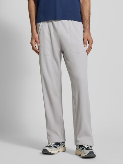 Mannenmodel draagt Straight fit Sweatpants met structuurpatroon model 'Essentials' van adidas Originals, katoenmix materiaalmix, elastische band, steekzakken, binnenbeenlengte maat M 77 cm, lichtgrijs, ganzkörperansicht van voren.