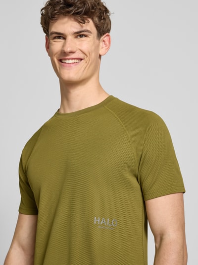 Männermodel trägt T-Shirt mit Label-Print Modell 'SORONA' von HALO in Olivgrün, feine Mesh-Textur, Rundhalsausschnitt, Regular Fit, Nahaufnahme Oberkörper.