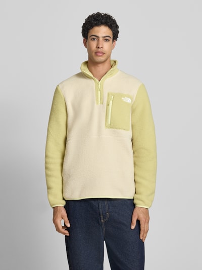 Männermodel trägt Fleecepullover mit Brusttasche Modell 'YUMIORI' von The North Face in Beige-Gelb, Regular-Fit, Stehkragen, Label-Stitching, Reißverschluss, Rückenlänge 70 cm, Ärmellänge 67 cm, Ganzkörperansicht von vorne.