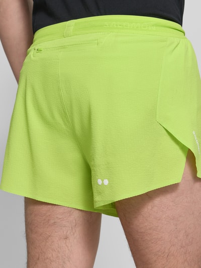 Männermodel trägt Shorts mit elastischem Bund Modell 'SENSE AERO' von Salomon aus Material-Mix mit Stretch-Anteil in Neongelb, Detailaufnahme Rückansicht. Regular-Fit, Bundweite 38 cm, Innenbeinlänge 7 cm.