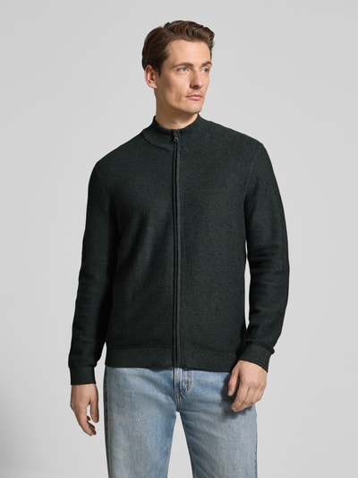 Męski model nosi Regular Fit Cardigan mit Stehkragen od OLYMP Level Five, czarna dzianina, bawełna, zamek, krój regular fit, widok z przodu, ujęcie całej sylwetki.