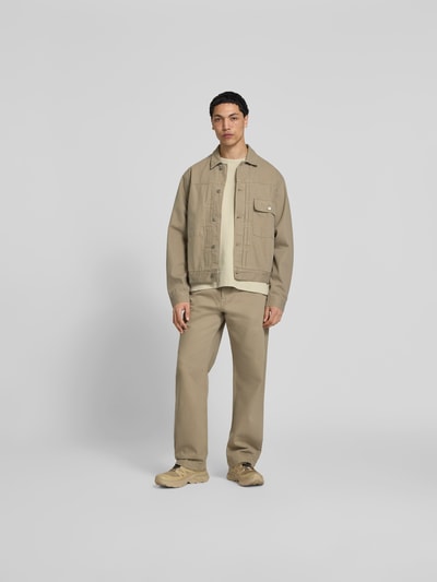 Männermodel trägt Straight Fit Jeans mit Gesäßtaschen von Forét aus Reine Baumwolle, beige, mit Eingrifftaschen und Knopf-Reißverschluss, Ganzkörperansicht von vorne.