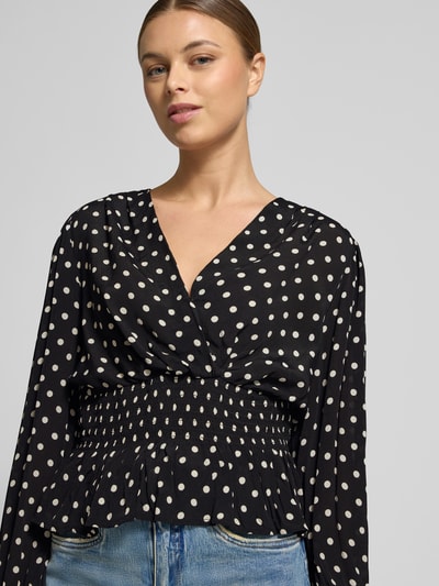 Frauenmodel trägt Bluse aus reiner Viskose in Wickel-Optik Modell 'Tamona' von Neo Noir, Regular Fit, tailliert, Rüschen, gepunktet, Nahaufnahme Oberkörper.