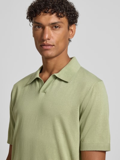 Męski model nosi Slim Fit Poloshirt aus Lyocell-Baumwoll-Mix od OLYMP Level Five, kołnierzyk polo, krótki rękaw, długość tyłu w rozmiarze M: 68 cm, jasna zieleń, gładka tekstura, zbliżenie na górną część ciała, widok z przodu.