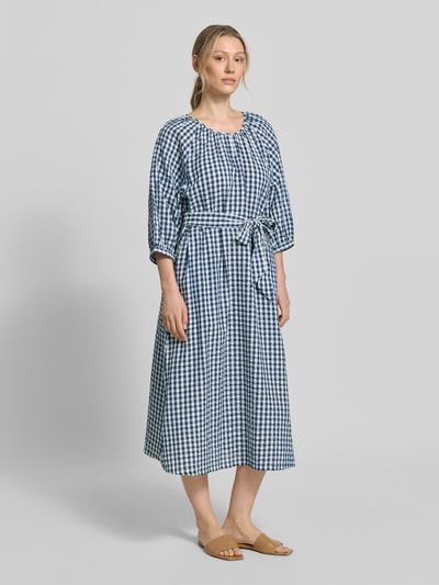 Modelka kobieca nosi Regular Fit Freizeitkleid aus reiner Baumwolle od s.Oliver RED LABEL w niebiesko-białą kratę, krój regular fit, długość midi, dekolt okrągły, rękaw 3/4, prosty dół, pasek wiązany, bawełna crinkle, widok całej sylwetki z przodu.