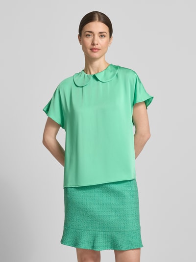 Modelka kobieca nosi Blusenshirt aus Satin mit Umlegekragen von Marc Cain, satynowy, krój regular fit, zielony, długość tyłu 59 cm, długość rękawa 20 cm, zapięcie na guzik z tyłu, widok całej sylwetki z przodu.