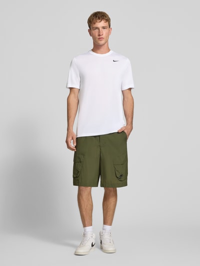 Männermodel trägt weißes T-Shirt mit Logo-Print und Rundhalsausschnitt von NIKE TRAINING, Regular Fit, strukturierte Stoffoptik, Ganzkörperansicht von vorne.