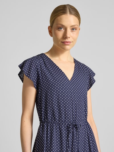 Vrouwenmodel draagt mini-jurk uit zuiver viscose met V-hals van GAP, getailleerde pasvorm, tunnelkoord in taille, met korte mouwen, borstwijdte maat S 85 cm, mouwlengte 11 cm, donkerblauw met witte stippen, textuur glad, nahaufnahme bovenlichaam.