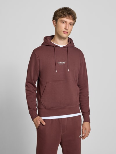 Männermodel trägt Regular Fit Hoodie aus Baumwoll-Mix Modell 'Soho' von JACK & JONES in Braun, Känguru-Tasche, Ganzkörperansicht von vorne.