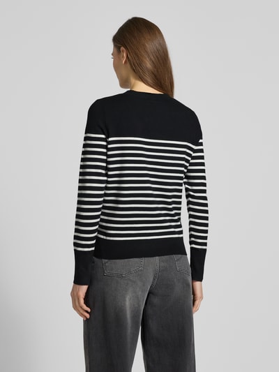 Modelka nosi Regular Fit Strickpullover aus Viskose-Mix od s.Oliver RED LABEL, efekt: wzór na całej powierzchni, krój regular fit, dekolt okrągły, długi rękaw, zakończenia prążkowane, dzianina, mieszanka wiskozy, widok całej sylwetki z tyłu.