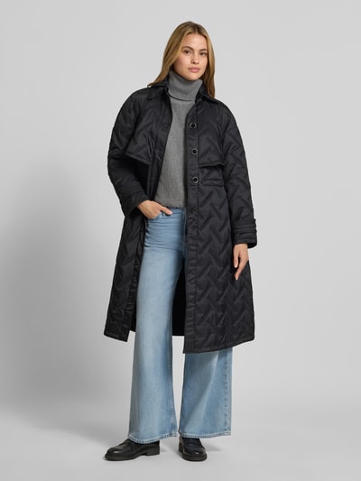 Frauenmodel trägt Regular Fit Mantel in Stepp-Optik von Emporio Armani, schwarz, Struktur mit Kapuze und Knopfleiste, Ganzkörperansicht von vorne.