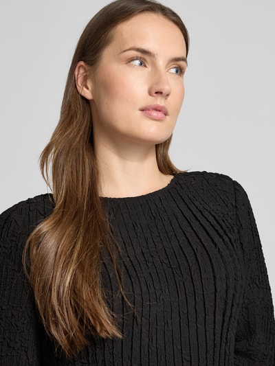 Vrouwenmodel draagt Tailliertes Cocktailkleid mit Raffung-Optik Modell 'Doppar' van BOSS in zwart met gestructureerd patroon, mini lengte, ronde hals, lange mouw met frill, details met ruches, sleutelgathalslijn achter, unicolor, aangesloten fit, close-up bovenlichaam