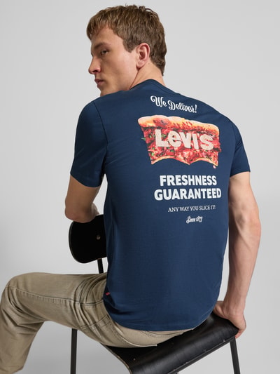 Männermodel trägt T-Shirt mit Label-Detail und Logo-Print von Levi's®, reine Baumwolle, körpernaher Schnitt, Rückenlänge 68 cm, Ganzkörperansicht Rückansicht.