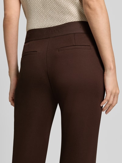 Frauenmodel trägt Flared Cut Hose aus Viskose-Mix mit Gesäßtaschen von Christian Berg Woman in Dunkelbraun, glatte Struktur, Nahaufnahme Rückansicht.