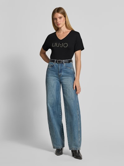 Frauenmodel trägt Regular Fit T-Shirt aus reiner Baumwolle von Liu Jo White, Schwarz, Ziersteinbesatz, Logo-Detail, Ganzkörperansicht von vorne.