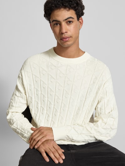 Männermodel trägt Strickpullover mit Rundhalsausschnitt Modell 'EASY' von Calvin Klein Jeans in Weiß, strukturierte Oberfläche, Nahaufnahme Oberkörper, reine Baumwolle, Regular Fit.