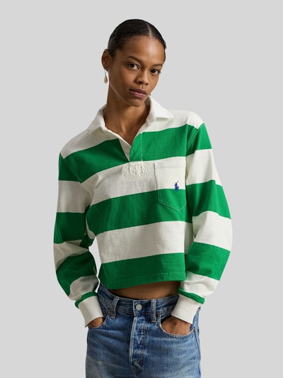 Kobiece modelka nosi Regular Fit Poloshirt aus reiner Baumwolle od Polo Ralph Lauren, zielono-białe paski, logo na kieszonce, długi rękaw, piqué, krój regular fit, widok z przodu, zbliżenie na górną część ciała.