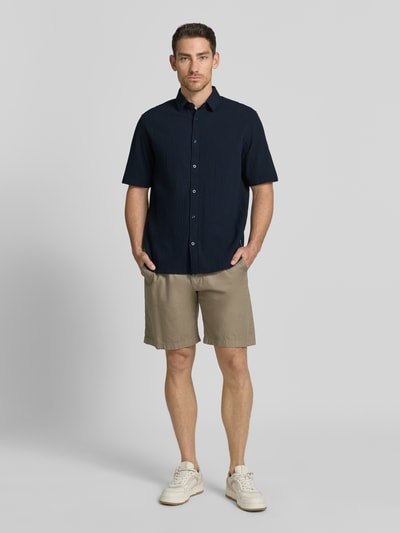 Männermodel trägt Comfort Fit Freizeithemd aus Lyocell-Baumwoll-Mix von Tom Tailor, Optik: Unifarben, Struktur, Crinkle, Kentkragen, Kurzarm, Ganzkörperansicht von vorne.