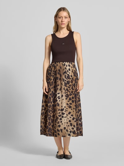 Frauenmodel trägt Midikleid mit Eingrifftaschen von Smith and Soul aus elastischem Baumwoll-Modal-Mix in Braun mit Leo-Muster, taillierte Passform, Rundhalsausschnitt, Ganzkörperansicht von vorne.