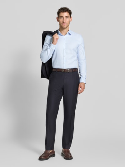Męski model trägt Slim Fit Businesshemd aus bawełny mit kołnierzykiem typu kent von Jake*s, listwa guzikowa, ciemnoniebieskie spodnie, długość tyłu w rozmiarze 39/40: 77 cm, szerokość ramion w rozmiarze 39/40: 45 cm, długość rękawów w rozmiarze 39/40: 64 cm, jasnoniebieska koszula na tle szarym, ganzkörperansicht von vorne.