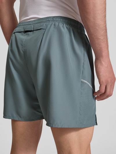Männermodel trägt Shorts mit seitlichen Eingrifftaschen und Logo-Print von NIKE TRAINING in Grau, Loose-Fit, elastischer Bund, Ganzkörperansicht Rückansicht.