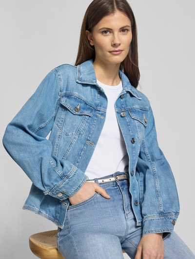 Modelka kobieca nosi Regular Fit Jeansjacke mit Brusttaschen od Liu Jo White z bawełny, taliowany krój, niebieski denim, szerokość ramion w rozmiarze S: 39 cm, długość tyłu: 54 cm, szerokość klatki piersiowej w rozmiarze S: 42 cm, długość rękawów: 59 cm, wykładany kołnierz, sportowe mankiety, guziki z przodu, widok na górną część ciała z przodu.