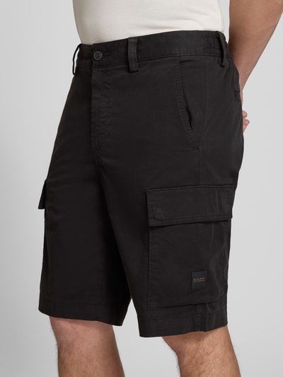 Männermodel trägt Relaxed Fit Cargoshorts aus Baumwoll-Mix Modell 'SISLA' von BOSS Orange in Schwarz, unifarben, Nahaufnahme Oberschenkel.