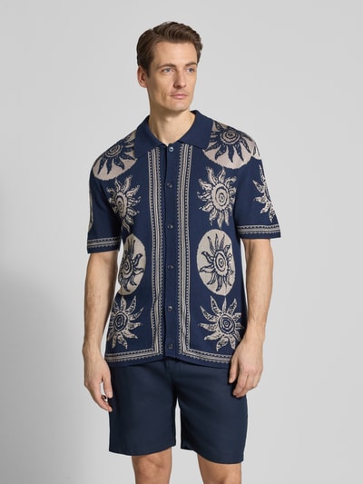 Männermodel trägt Strickshirt mit Polokragen und Knopfleiste von Scotch & Soda im Allover-Look, Baumwoll-Viskose-Mix, Regular-Fit, Ganzkörperansicht von vorne.