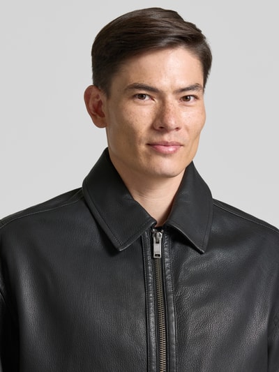 Mężczyzna model nosi Regular Fit Lederjacke aus echtem Ziegenleder Modell 'JOSUAL' von BOSS Orange, czarna faktura skóry, zbliżenie na górną część ciała