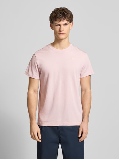 Męski model nosi T-Shirt aus Baumwolle od G-Star Raw w jasnoróżowym kolorze, prosty krój, okrągły dekolt, wyhaftowane logo, długość tyłu 71 cm w rozmiarze M, całkowity widok z przodu.
